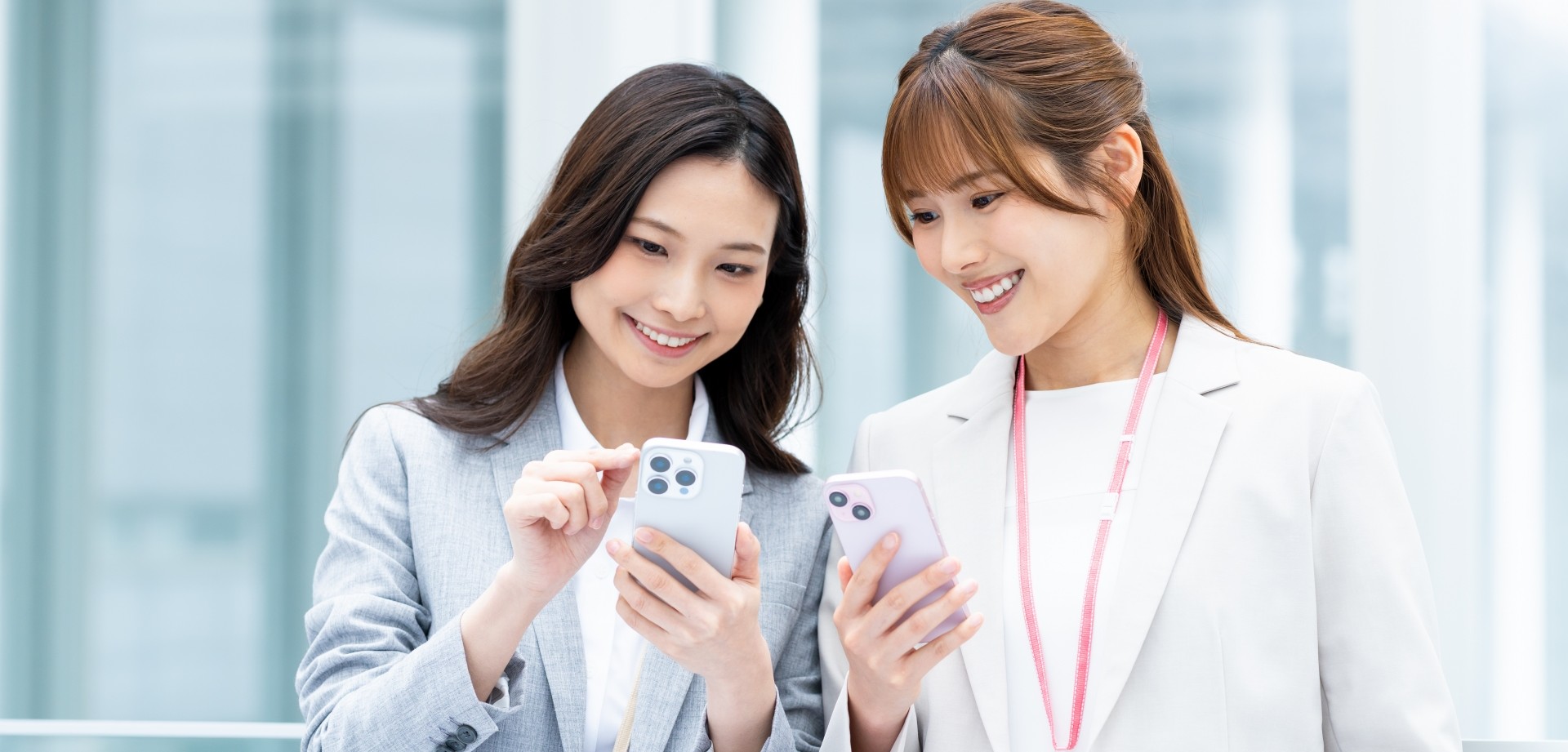 サンクスカードアプリで届いたサンクスカード見ながら話す女性社員2人の写真。